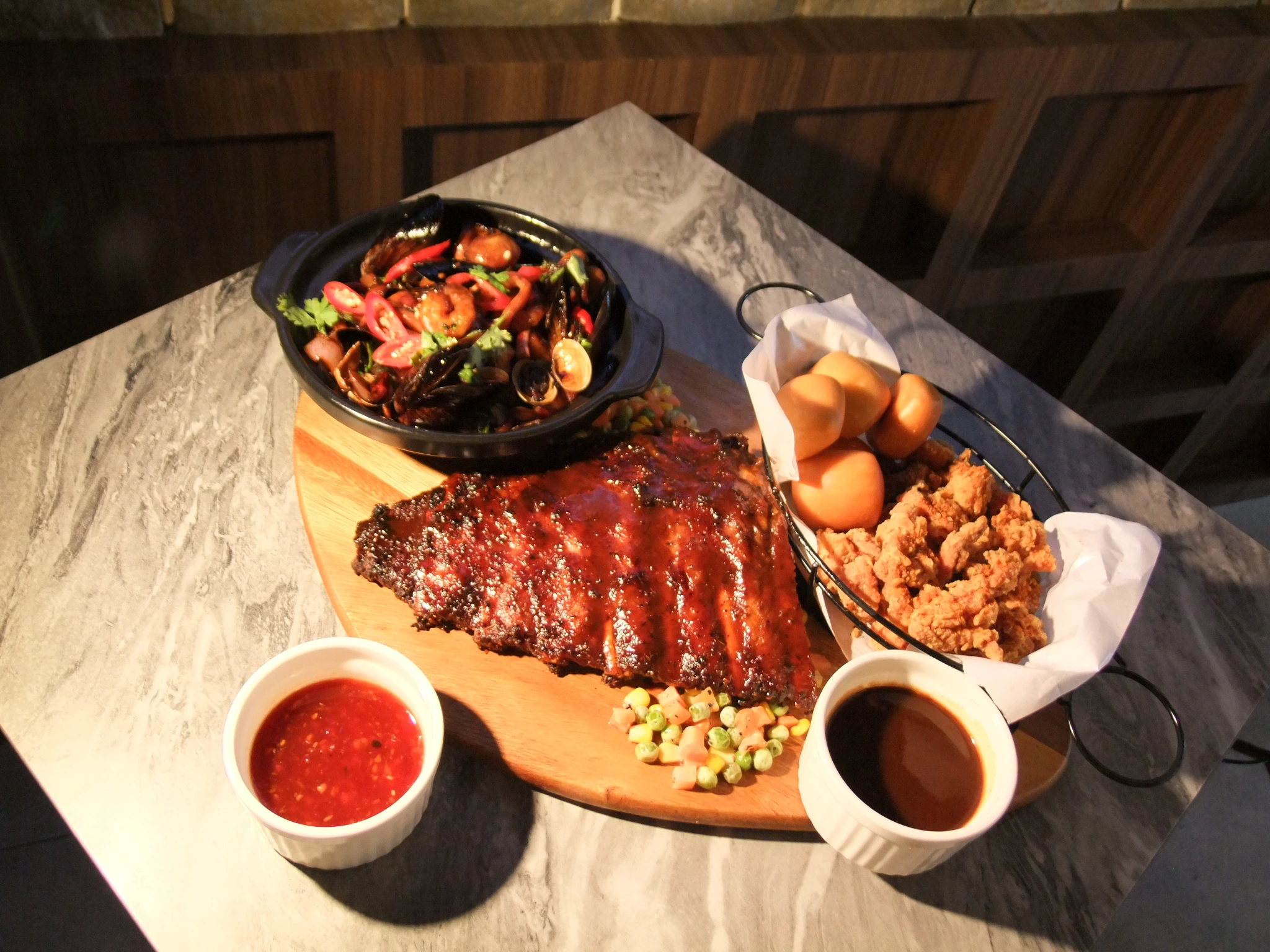 Sharing platter at Crave Castle Kitchen & Bar with glazed ribs, fried chicken and golden buns, a spicy stir-fried dish and two dipping sauces